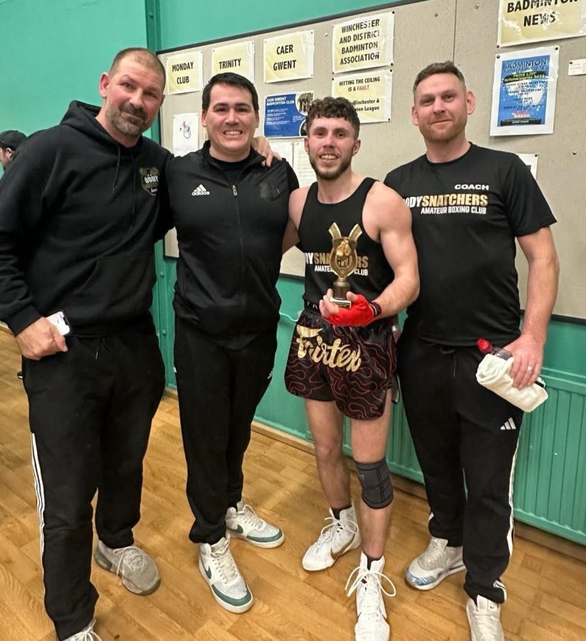 photo showing 4 people posing to camera after a wrestling win